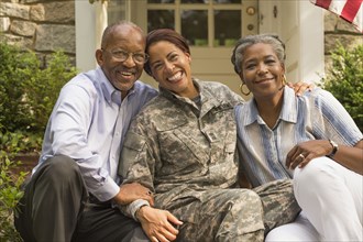 Portrait of soldier sitting on front stoop with parents