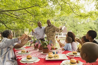 Soldier and multi-generation family toasting with lemonade at picnic