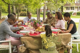 Multi-generation family praying at picnic table