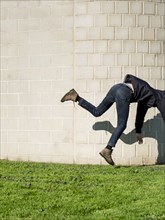 Caucasian man falling near brick wall