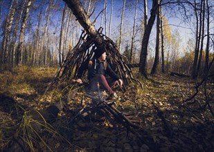 Man sitting in wooden shelter in forest