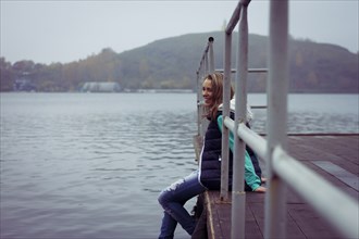 Caucasian woman sitting on dock over still lake