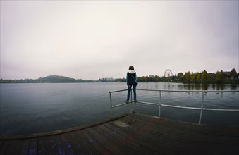 Caucasian woman standing on dock over still lake