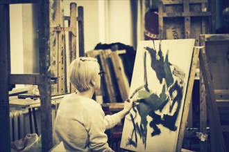 Caucasian artist painting on canvas in studio