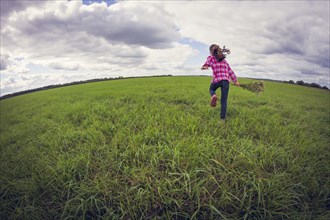 Caucasian girl running in grassy field