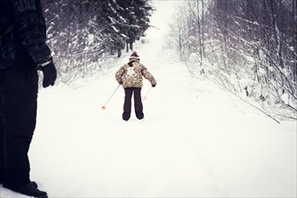 Caucasian father and daughter cross-country skiing on snowy road