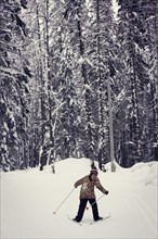 Caucasian girl cross-country skiing in forest