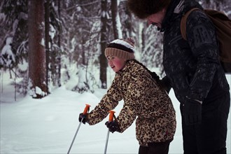 Caucasian father teaching daughter to cross-country ski in forest