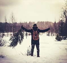 Caucasian man carrying tree in snowy field