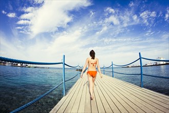 Caucasian girl walking on wooden dock over sea