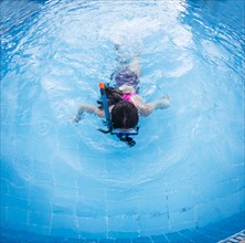 Caucasian girl snorkeling in swimming pool