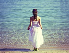 Caucasian girl wearing white dress on beach