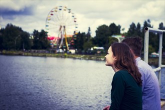 Couple standing at waterfront near ferris wheel