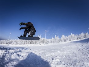 Caucasian snowboarder jumping on snowy slope