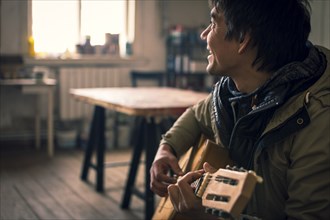 Asian man playing guitar indoors