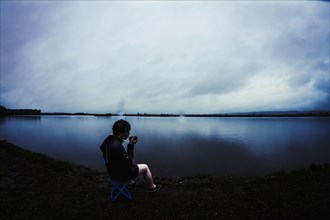 Caucasian man sitting by remote lake