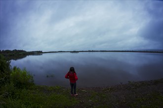 Caucasian teenage girl standing by remote lake