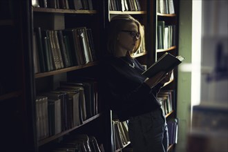 Caucasian woman reading book in library