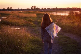 Caucasian teenage girl carrying kite on dirt path