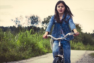 Caucasian teenage girl riding bicycle