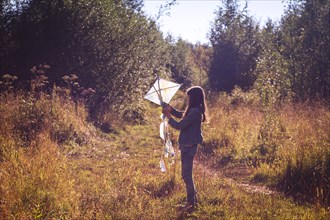 Caucasian teenage girl holding kite in field