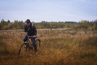 Caucasian man riding bicycle in field