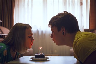 Couple blowing birthday candle on cupcake