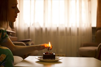 Caucasian woman lighting birthday candle on cupcake