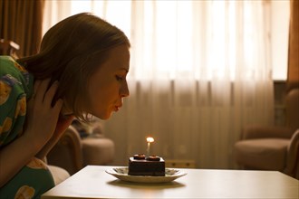 Caucasian woman blowing birthday candle on cupcake
