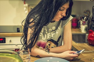 Caucasian woman using cell phone in kitchen