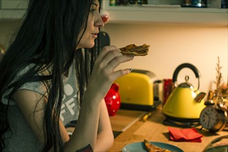 Caucasian woman eating pizza in kitchen