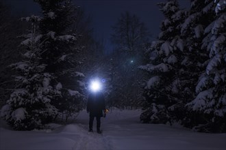 Caucasian hiker wearing headlamp in snowy forest