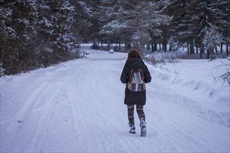 Caucasian woman walking on snowy rural road