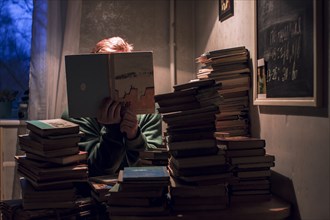 Caucasian man reading stack of books