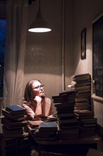 Caucasian woman sitting at stack of books