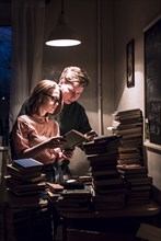 Caucasian couple reading stack of books