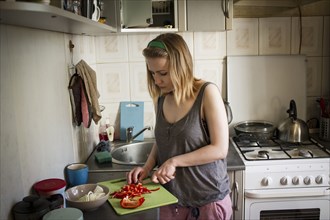 Caucasian woman cutting red peppers in kitchen