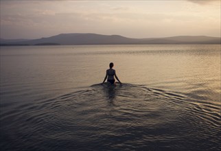 Silhouette of Caucasian woman wading in lake