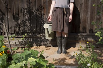 Caucasian woman holding watering can in garden