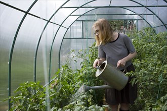 Caucasian woman watering greenhouse with watering can