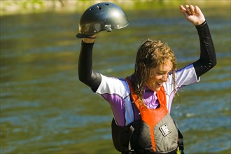 Wet Caucasian girl standing in river in kayak gear