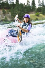 Caucasian teenager kayaking in river