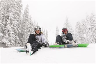 Snowboarders sitting in snow