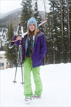 Skier carrying skis and ski poles
