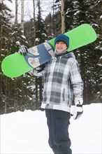 Mixed race snowboarder carrying snowboard
