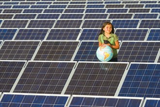 Native American girl standing near solar panels holding globe