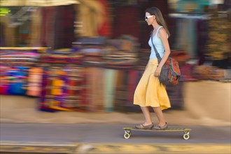 Caucasian woman skateboarding on sidewalk
