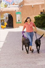 Hispanic woman walking dogs in town