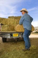 Hispanic man unloading hay from truck