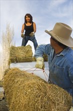 Hispanic couple loading hay